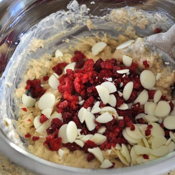 Healthy raspberry and white chocolate muffin batter in a bowl with a wooden spoon