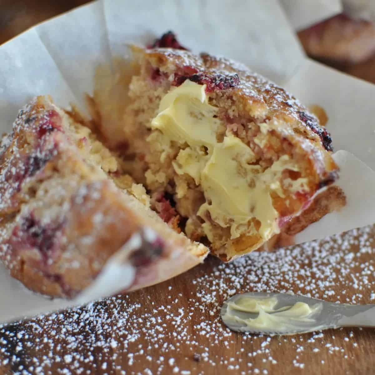 Healthy raspberry and white chocolate muffins cut and spread with butter