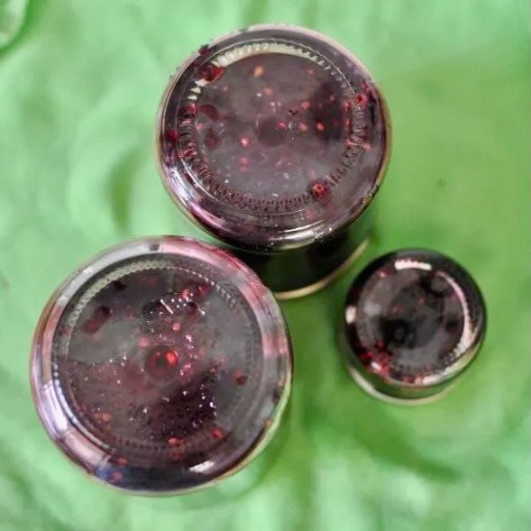 Mulberry jam jars upside down on a green background