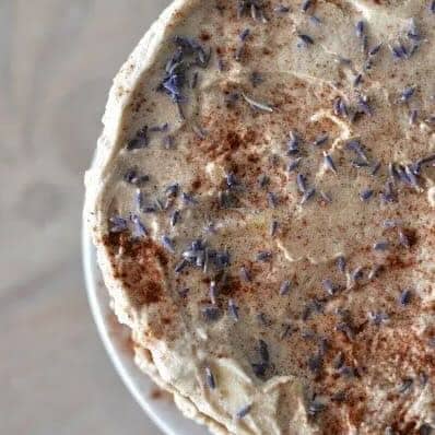 Two layer cinnamon pound cake with white icing in the middle and top sprinkled with lavender flowers