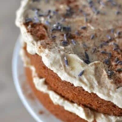 Two layer cinnamon pound cake with white icing in the middle and top sprinkled with lavender flowers