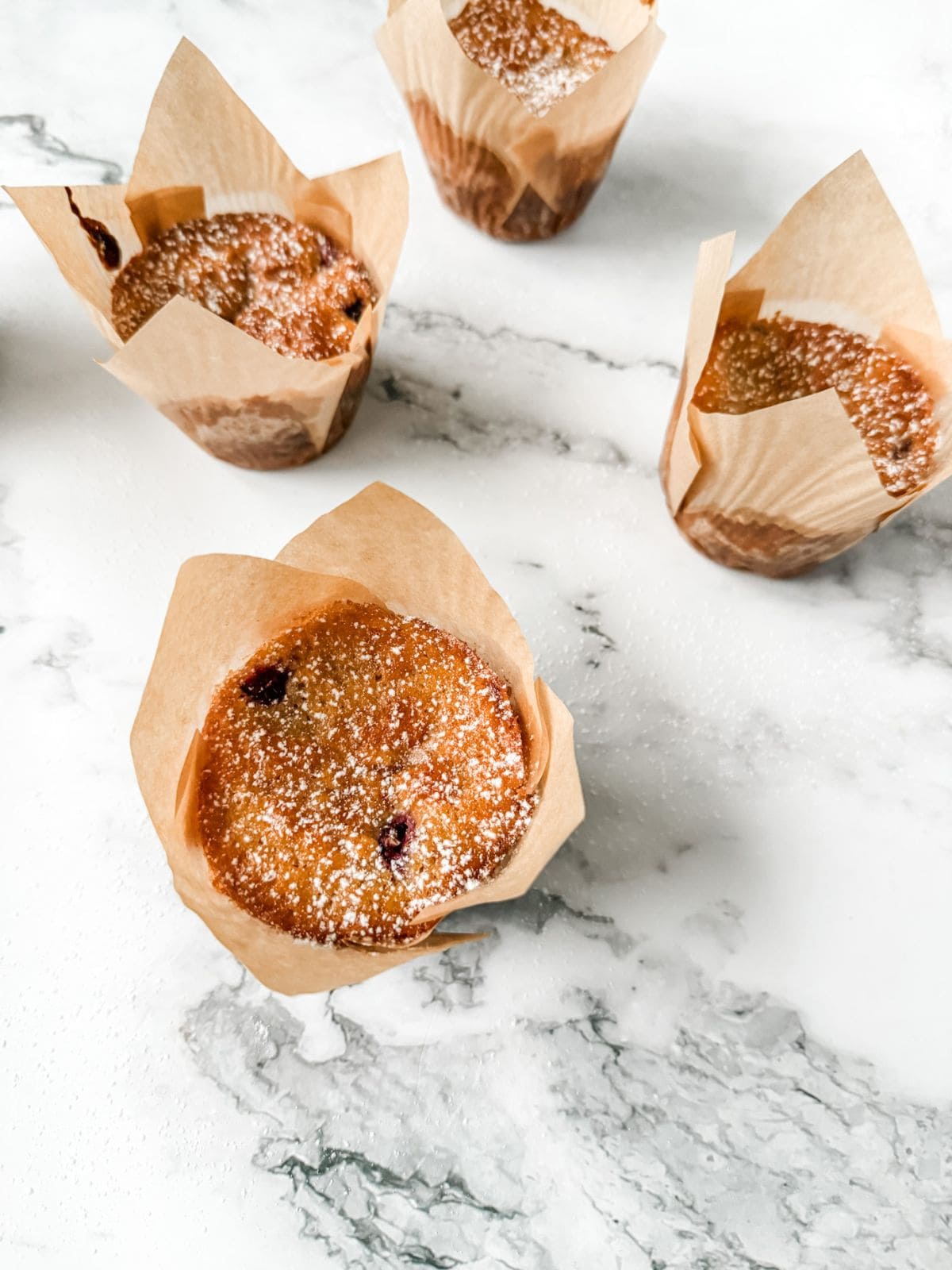 4 Healthy white chocolate and raspberry muffins on a white marble bench