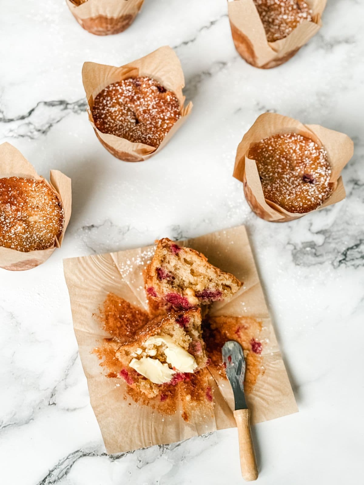 Raspberry and white chocolate muffin split in half spread with butter