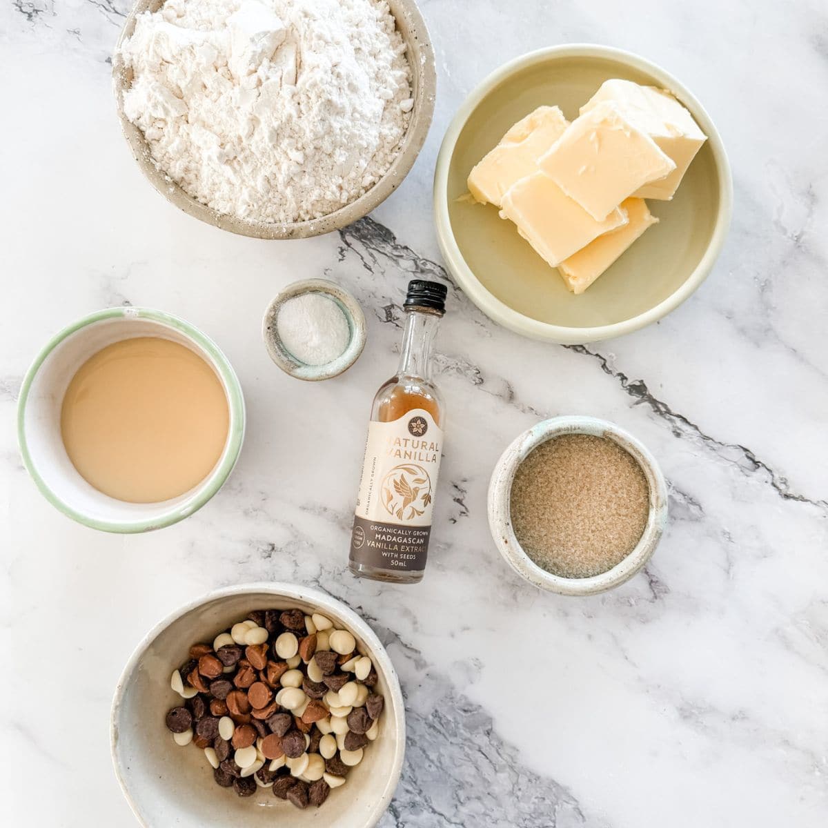 Ingredients for brown sugar walnut biscuits. Bowl of butter, brown sugar, mixed spice, bicarb, flour, walnuts and an egg & bottle of vanilla.