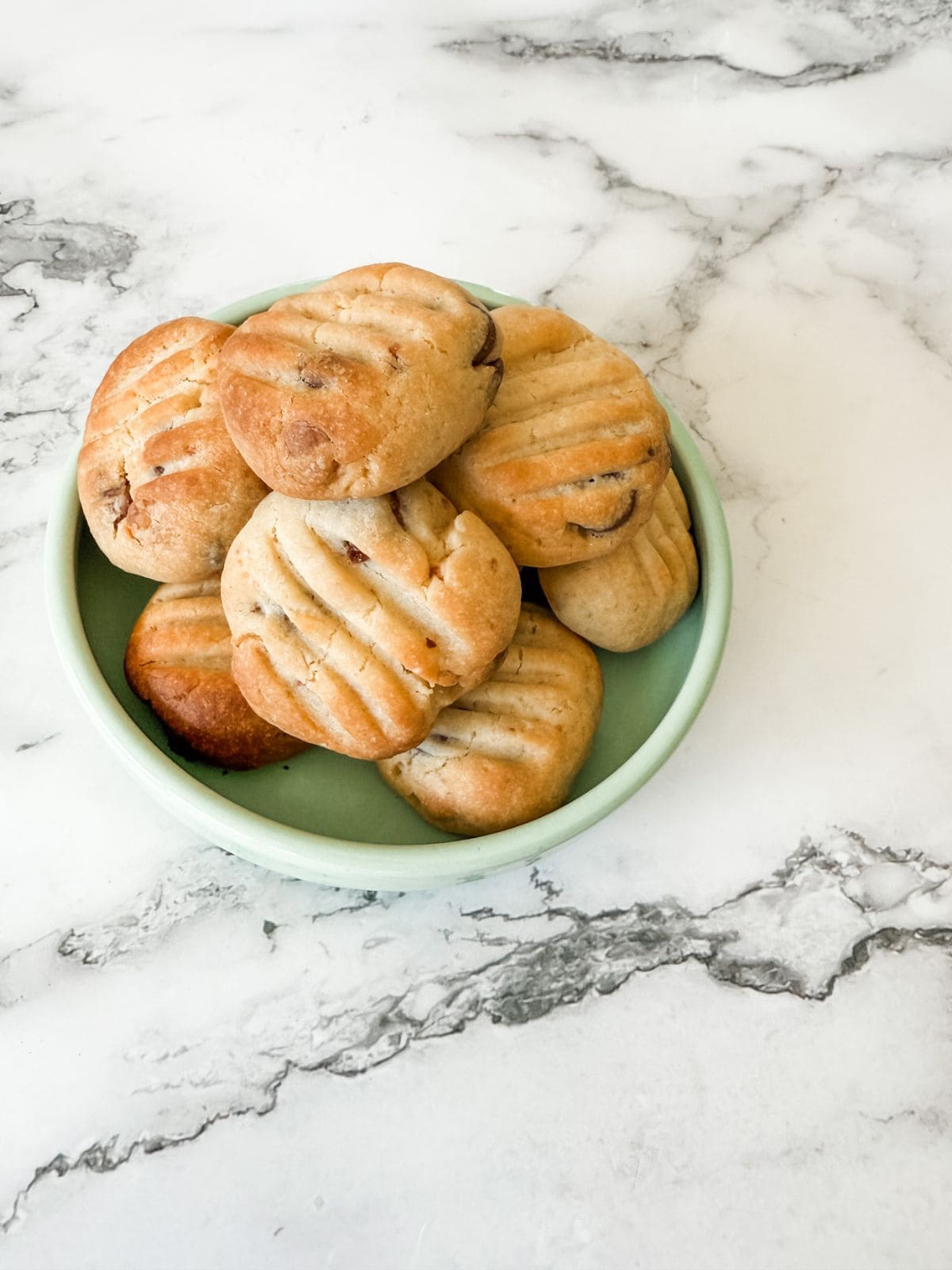 Bowl of chocolate chip Sante biscuits on a white marble bench top. 