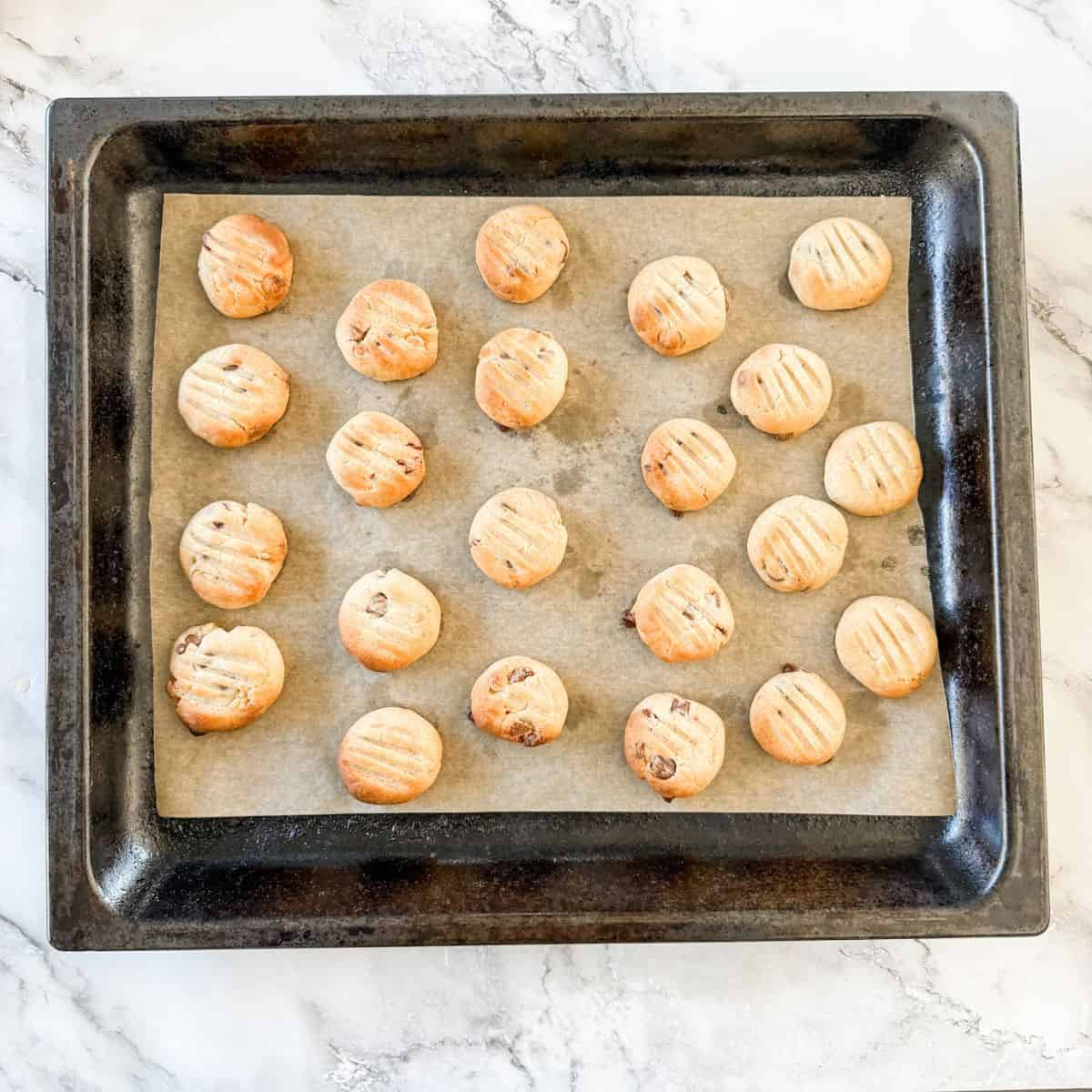 Baked chocolate chip Sante biscuits on a lined baking tray.