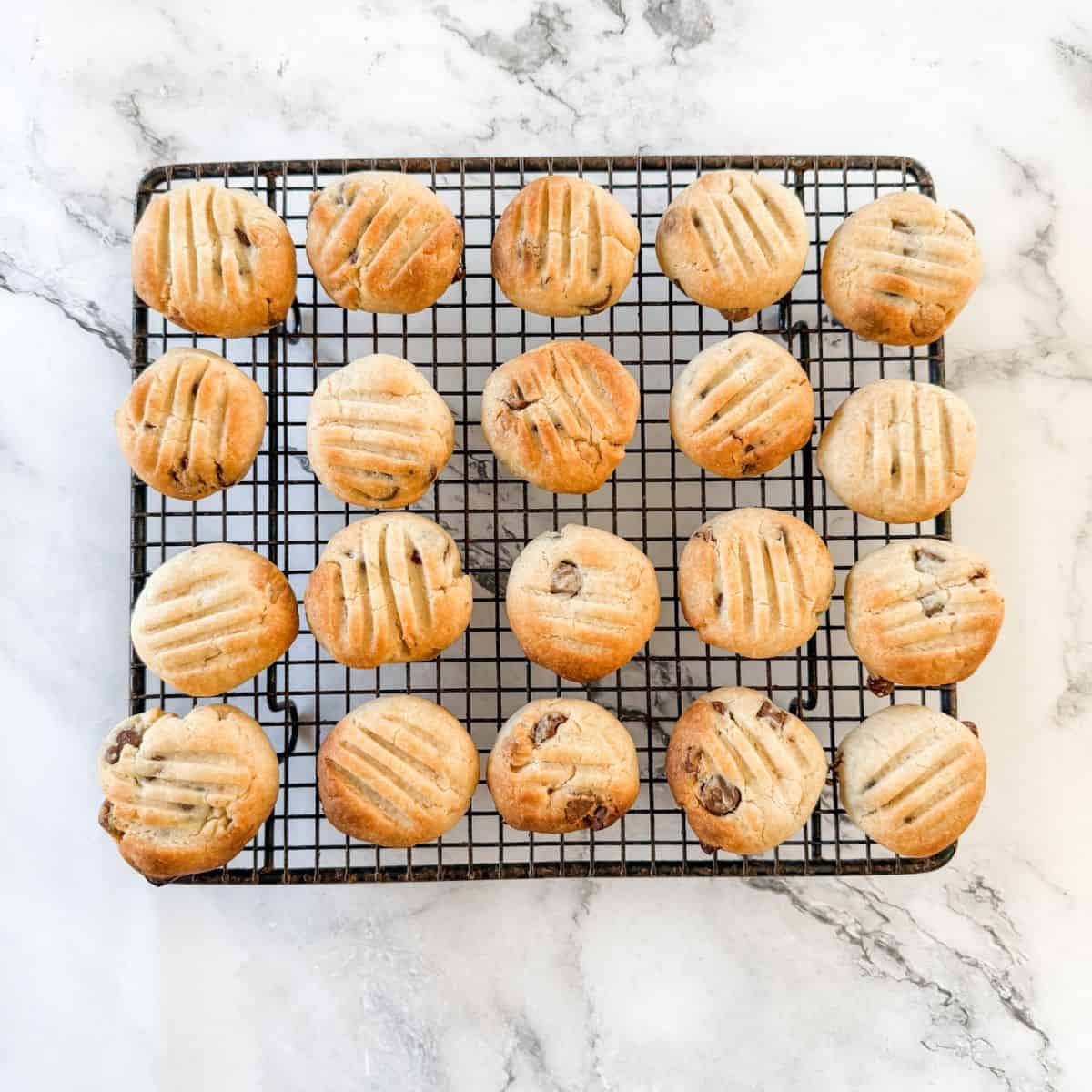 Baked chocolate Sante biscuits on a cooling tray on a white marble bench top.
