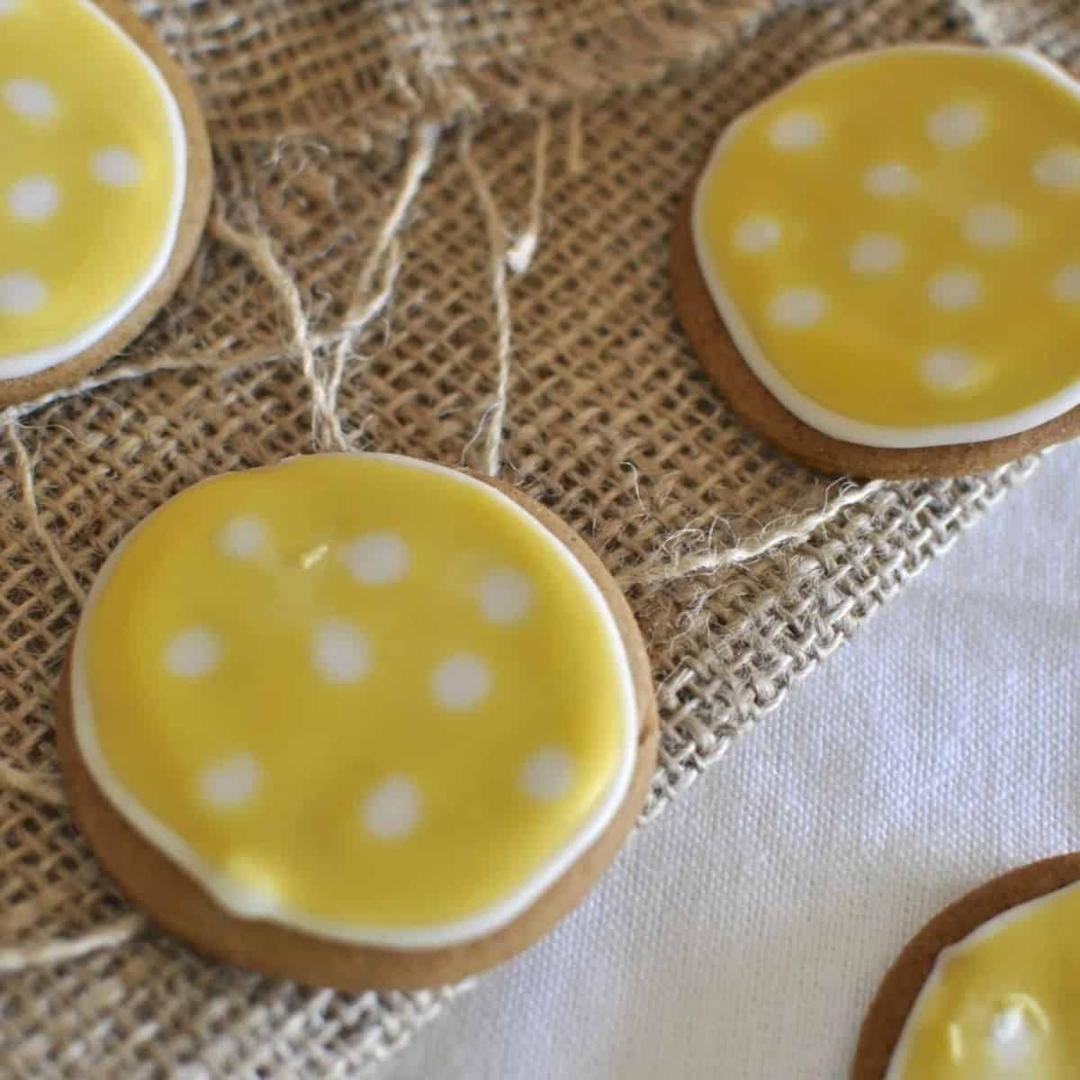 Round gingerbread cookies with yellow icing and spots.