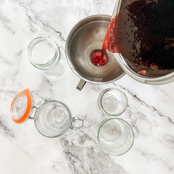 Pouring homemade strawberry jam into jars