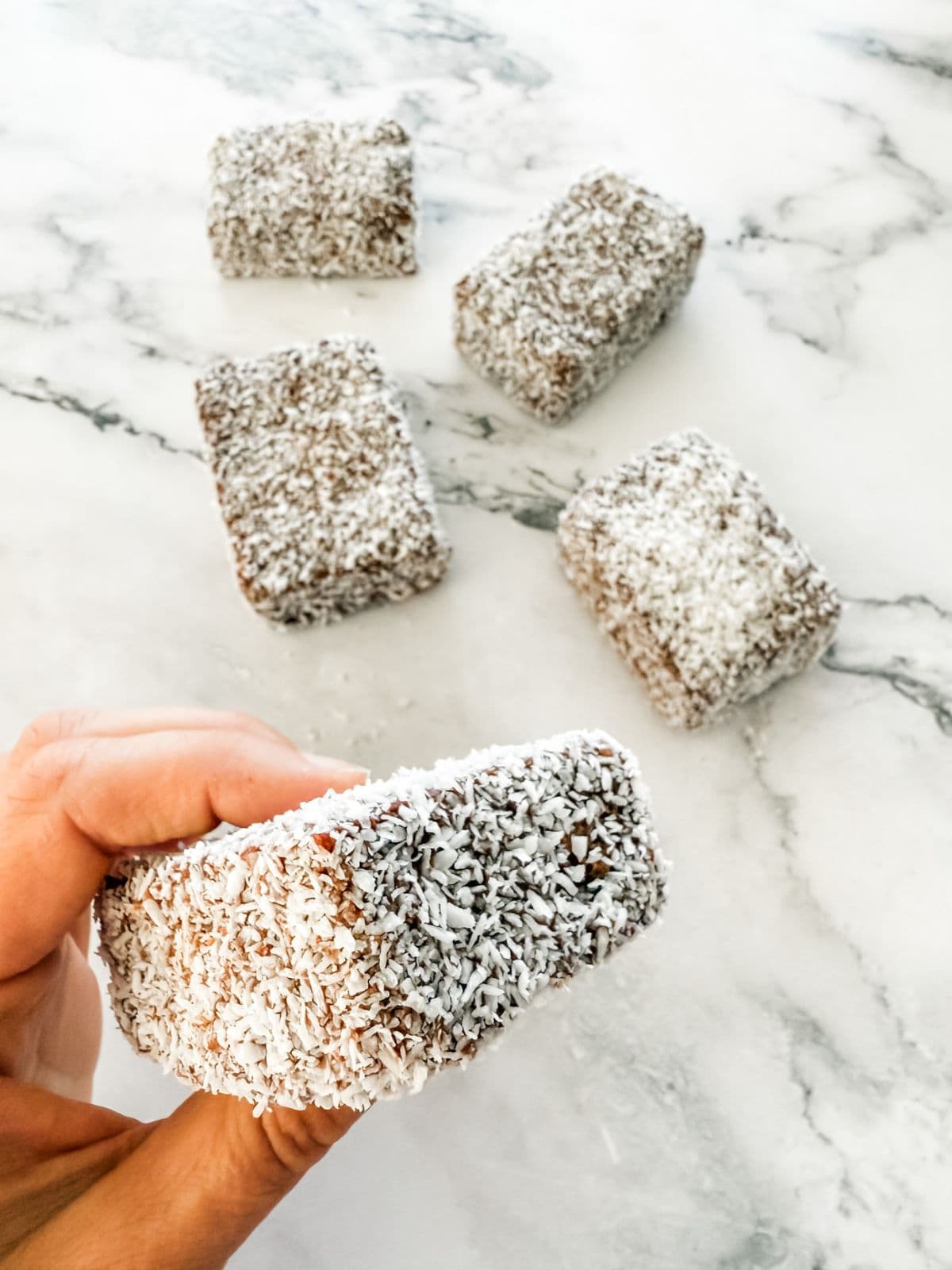 Homemade lamingtons in the Thermomix - hand holding a lamington