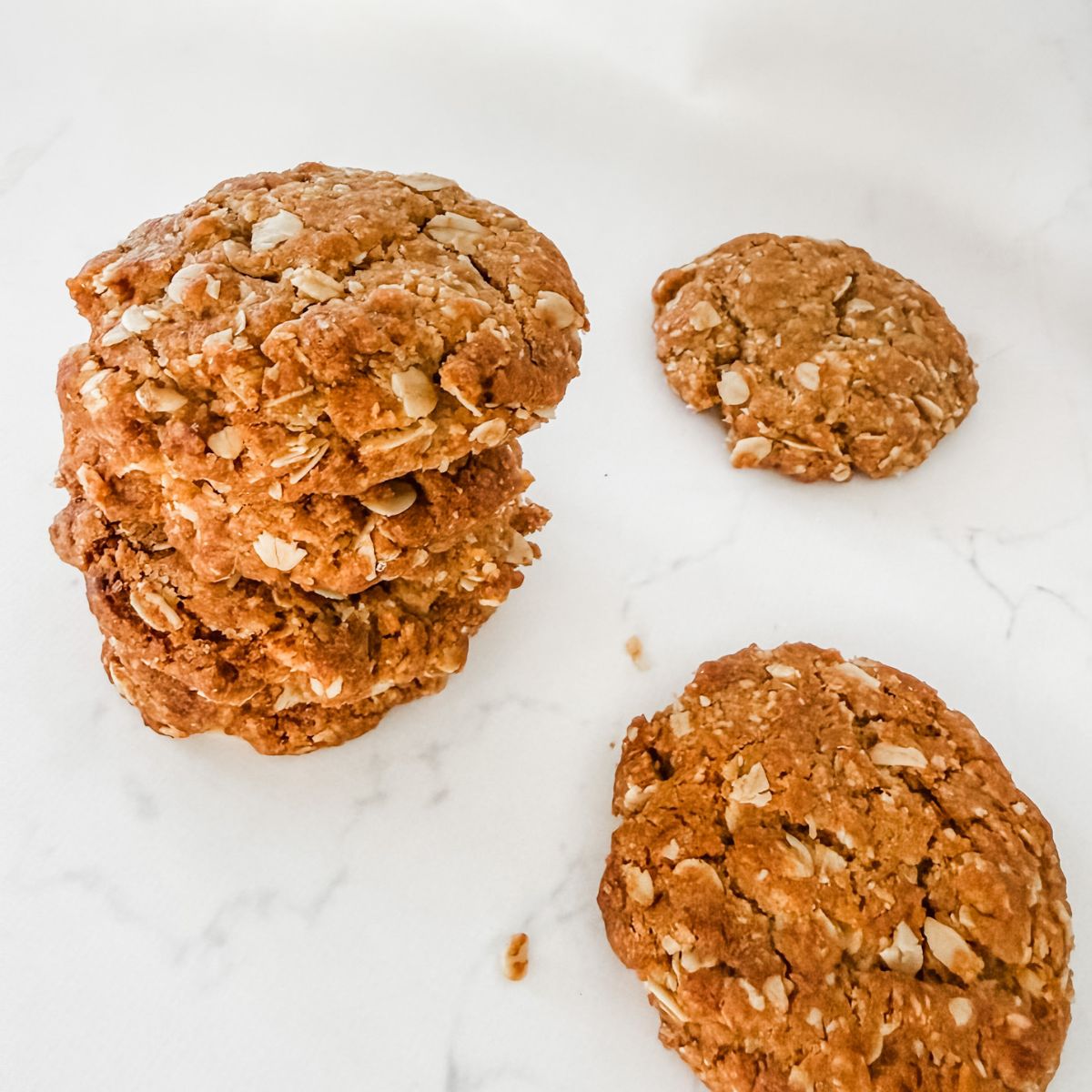 ANZAC biscuits in a stack on a white marble bench.