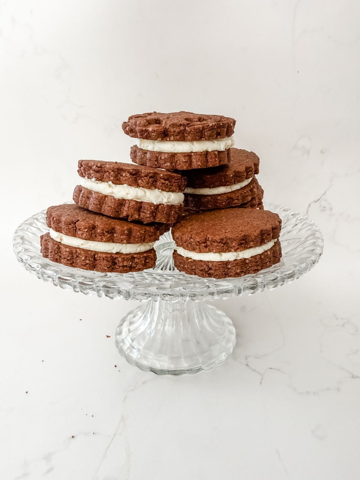 Stack of chocolate sandwich cookies on a cake stand.