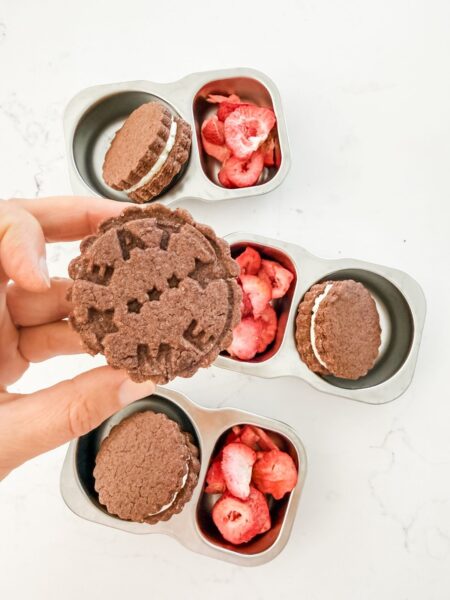 Chocolate sandwich cookie with eat me imprinted on it.
